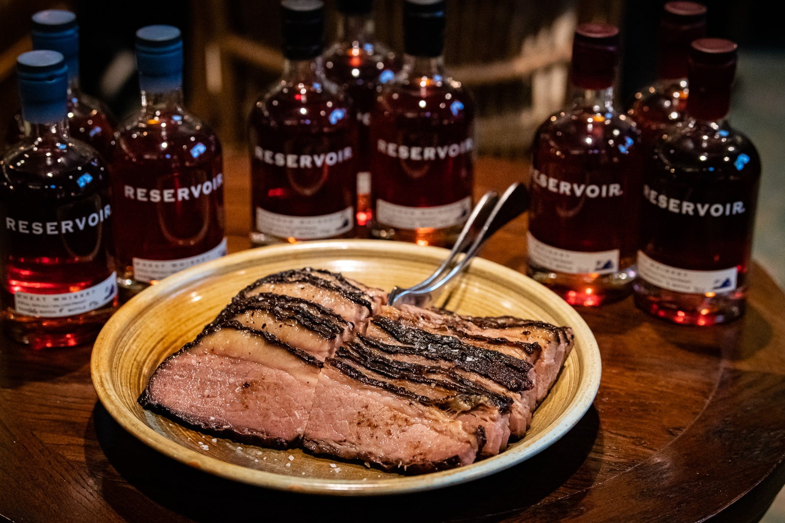 NOLA's Famous Beef Brisket Surrounded by Reservoir Distillery Whiskey Bottles